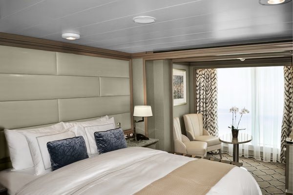 A luxurious Panorama Suite onboard the Silver Moon cruise ship, featuring elegant furnishings, a king-sized bed, and a sitting area with a view of the ocean.